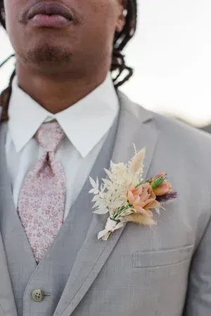 Man in a light gray suit with a floral tie and boutonniere on his lapel