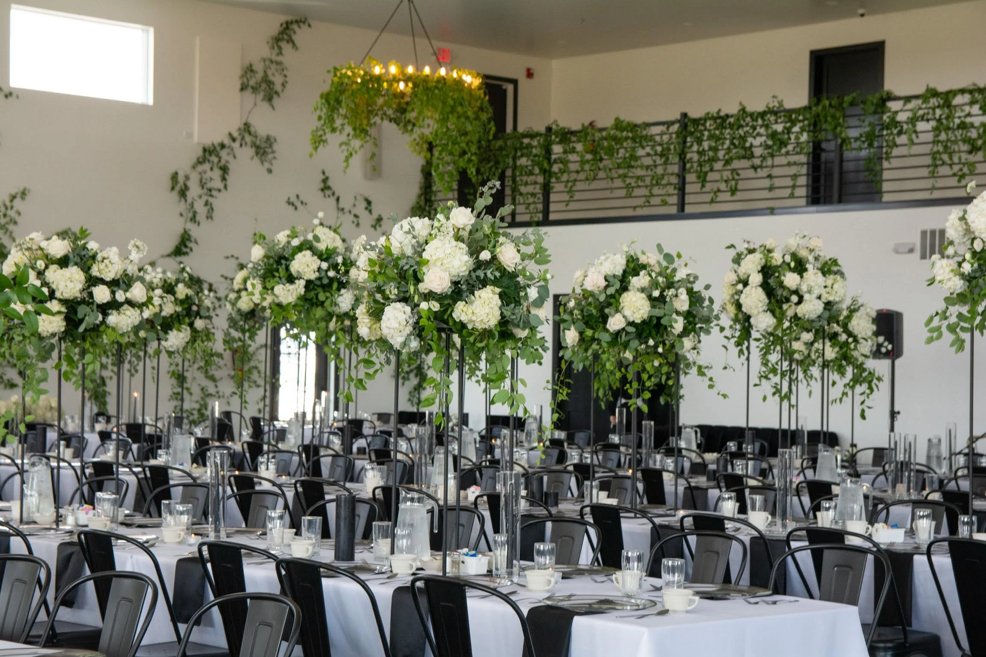 Elegant banquet hall with black-and-white decor and tall white floral centerpieces