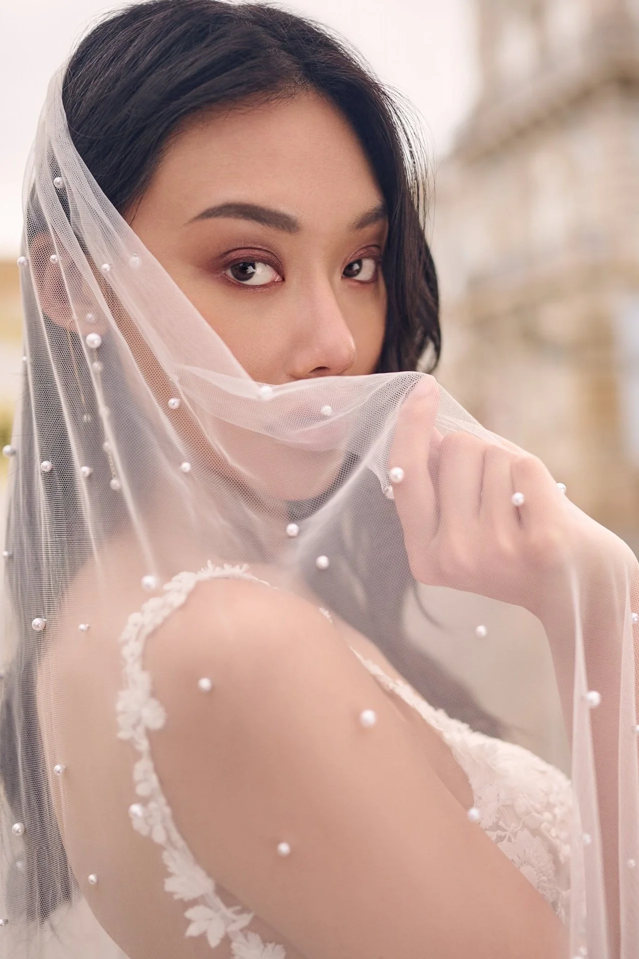 Woman in a sheer veil, looking at the camera with a soft, posed expression.