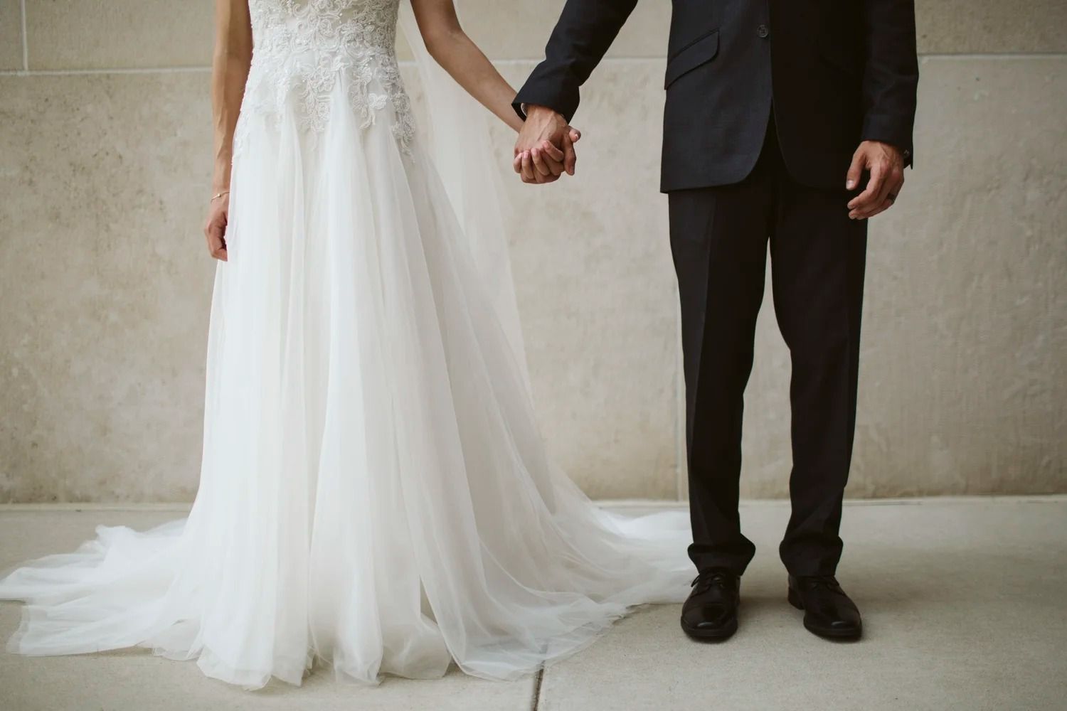 Bride and groom holding hands in a white wedding dress and black suit