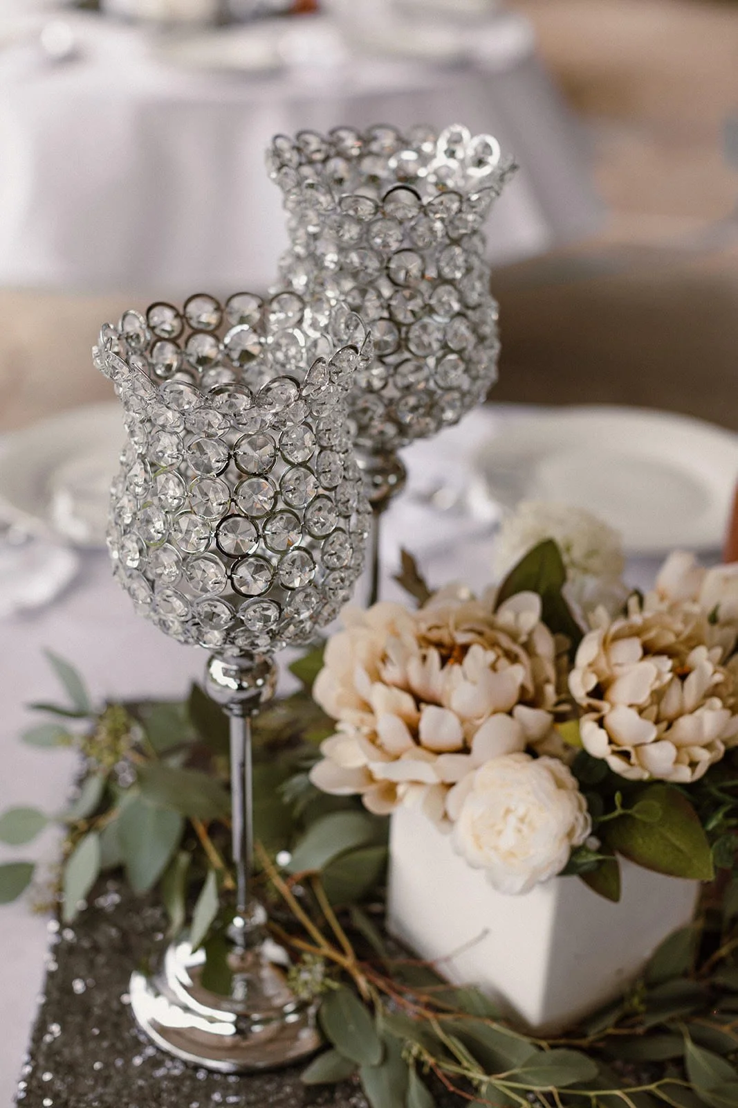 Crystal-studded champagne flute beside white flowers and greenery on a table setting