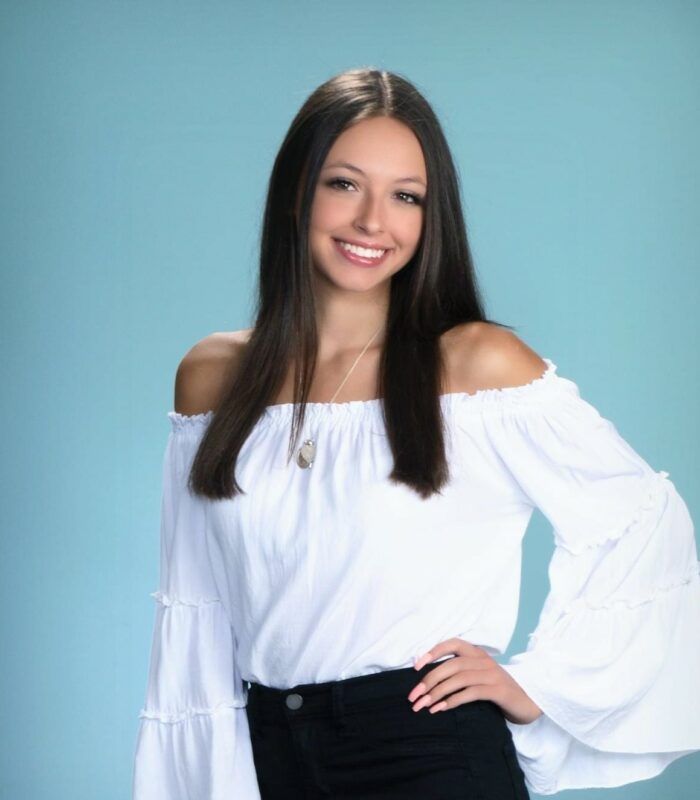 A woman wearing a white off the shoulder top and black jeans