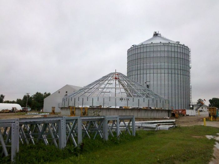 A large metal structure is being built on a farm