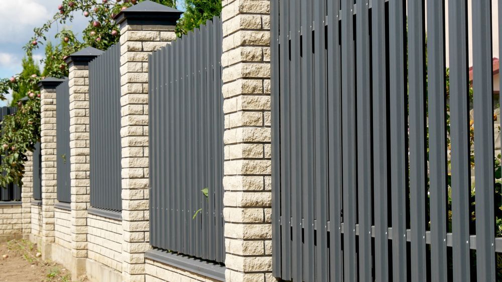 A Fence Made of Bricks and Metal is Surrounded by Brick Pillars — Sun City Sheetmetal In Mt Isa, QLD
