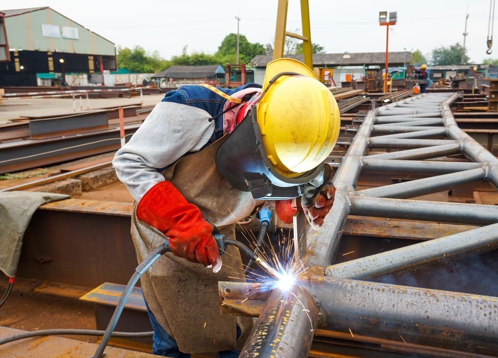 A Man is Welding a Metal Pipe in a Factory — Sun City Sheetmetal In Charters Towers, QLD