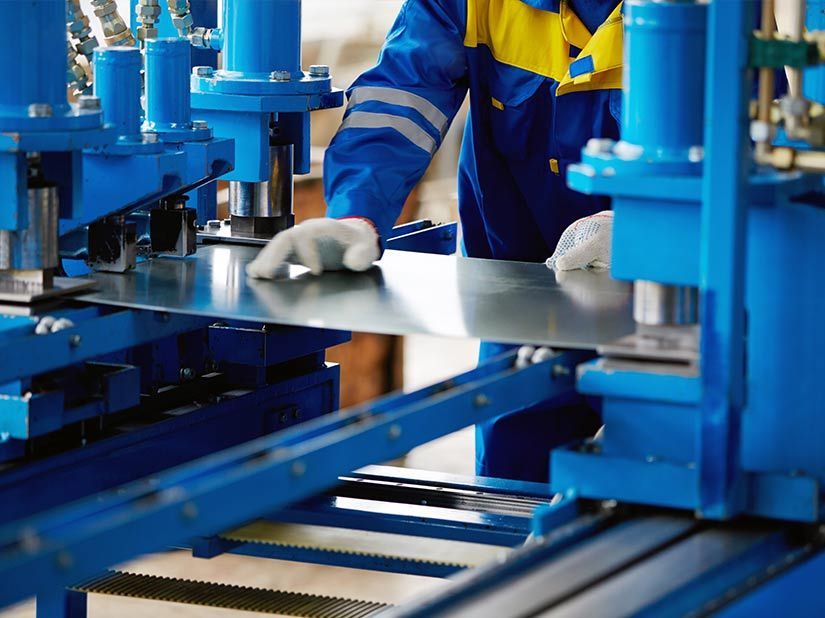 A Man in a Blue and Yellow Uniform is Working on a Machine — Sun City Sheetmetal In Garbutt, QLD
