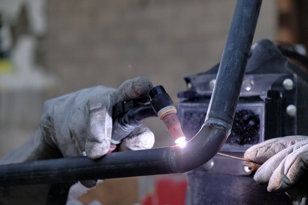 A Person is Welding a Pipe With a Torch — Sun City Sheetmetal In Garbutt, QLD