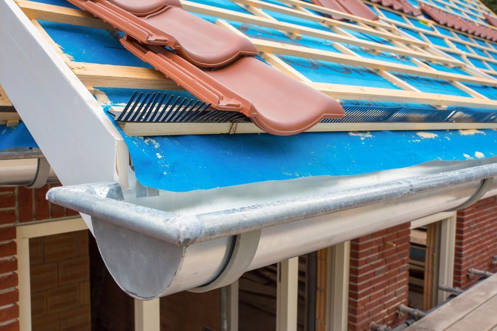 A Man is Using a Ladder to Install a Gutter on the Roof of a House — Sun City Sheetmetal In Garbutt, QLD