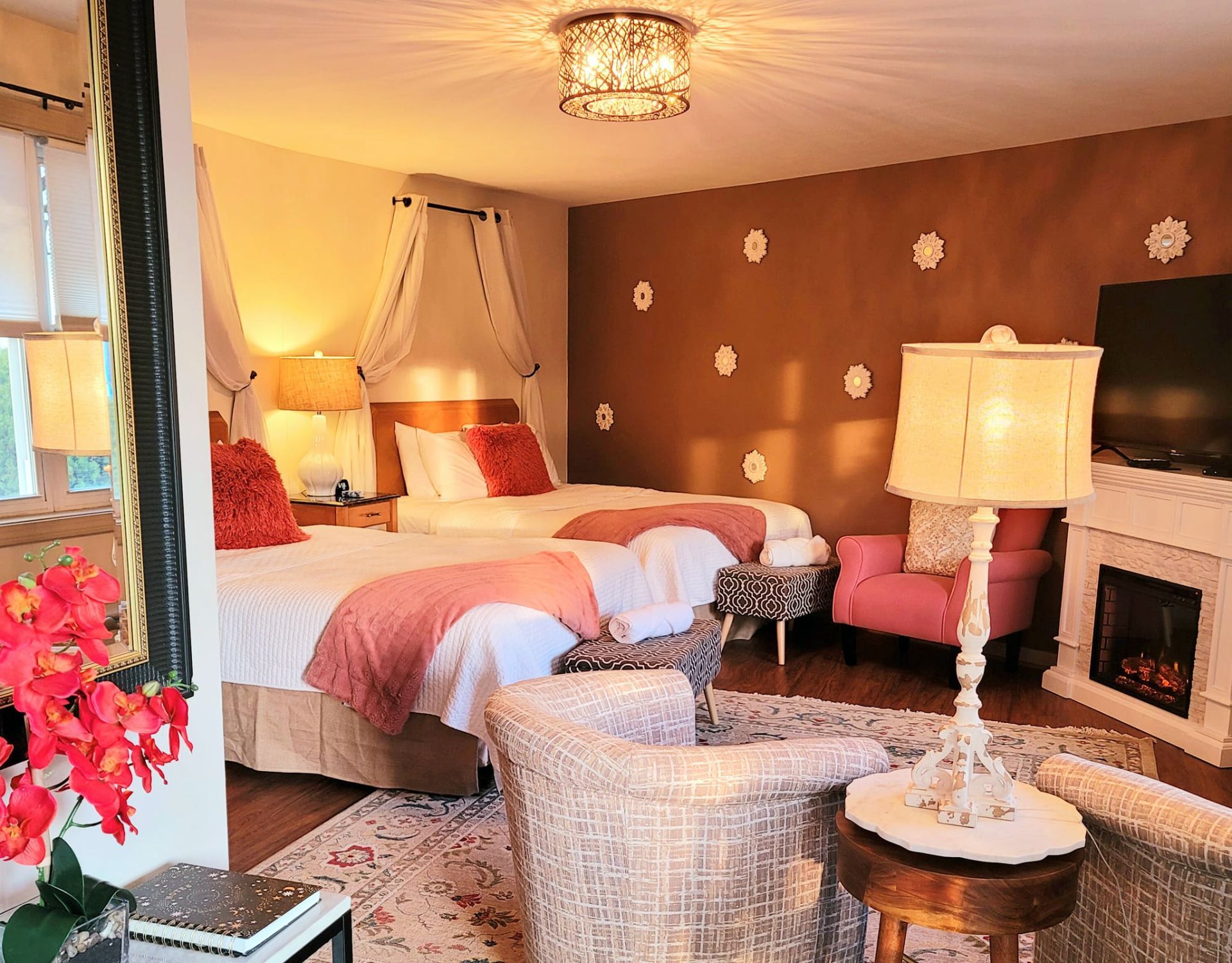 Bedroom with two beds, a fireplace, and sitting area. Warm colors and ornate decor.