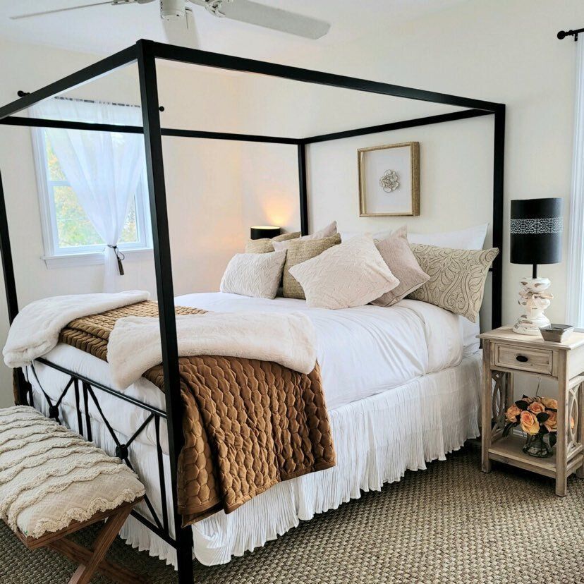 Bedroom with a black canopy bed, white bedding, and beige accents.