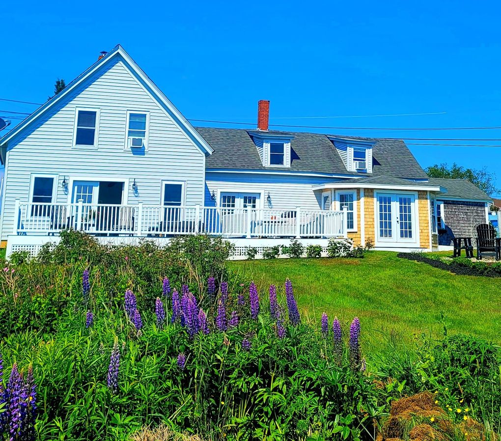 a large white house with purple flowers in front of it