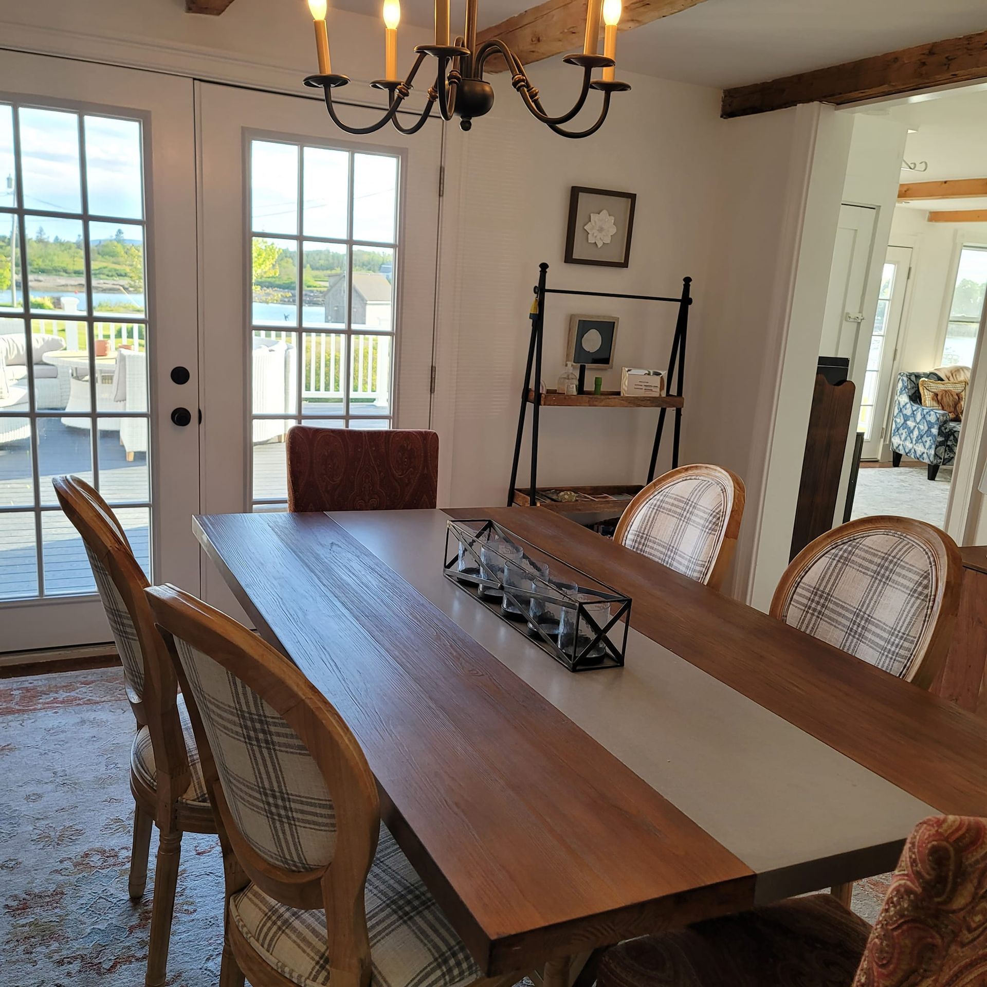 Dining room with a wooden table, six chairs, and a chandelier. Patio doors open to a deck.