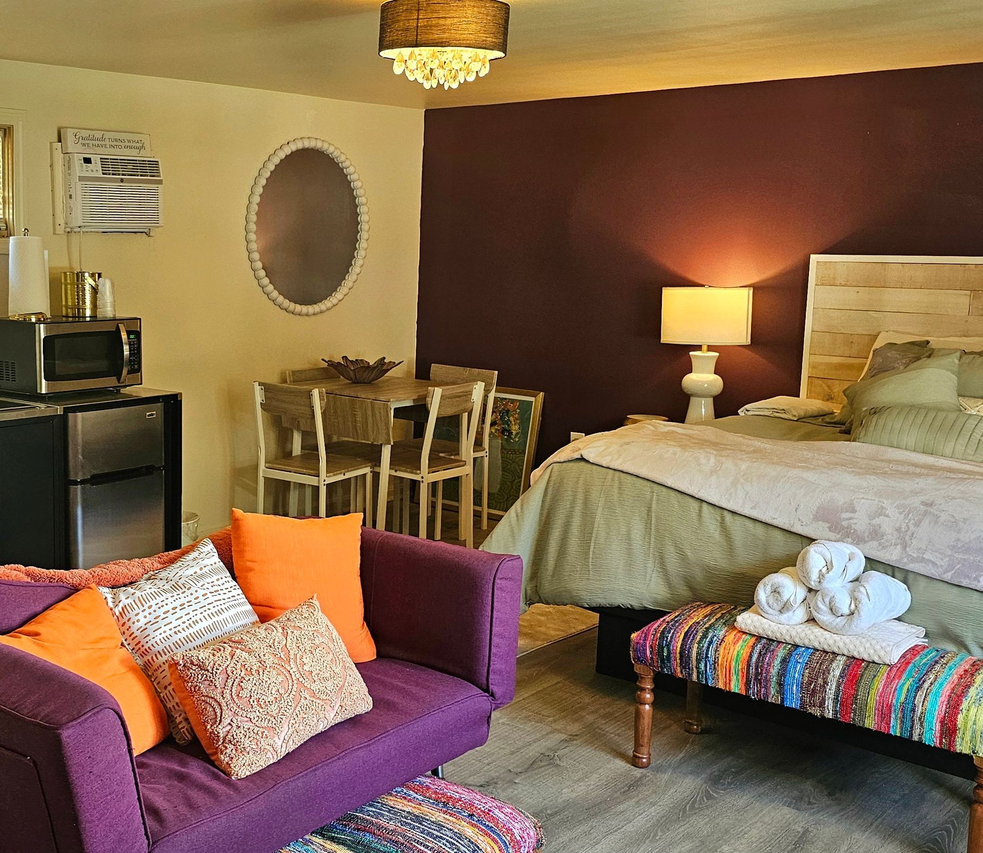 Small studio apartment with purple sofa, bed, and a dining area.