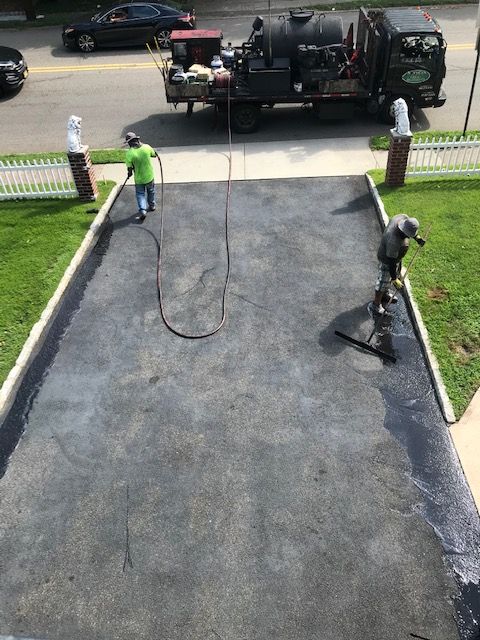 A group of men are laying asphalt in a driveway.