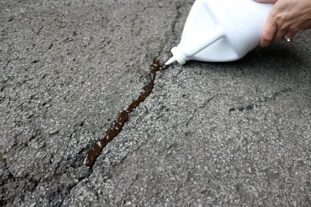 Driveway sealant being applied to cracked aspalt.