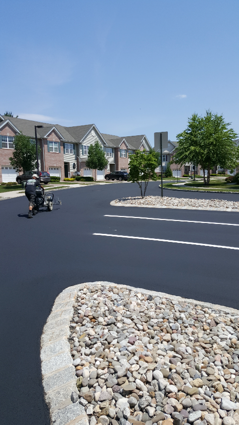 A man is painting a parking lot in a residential area.