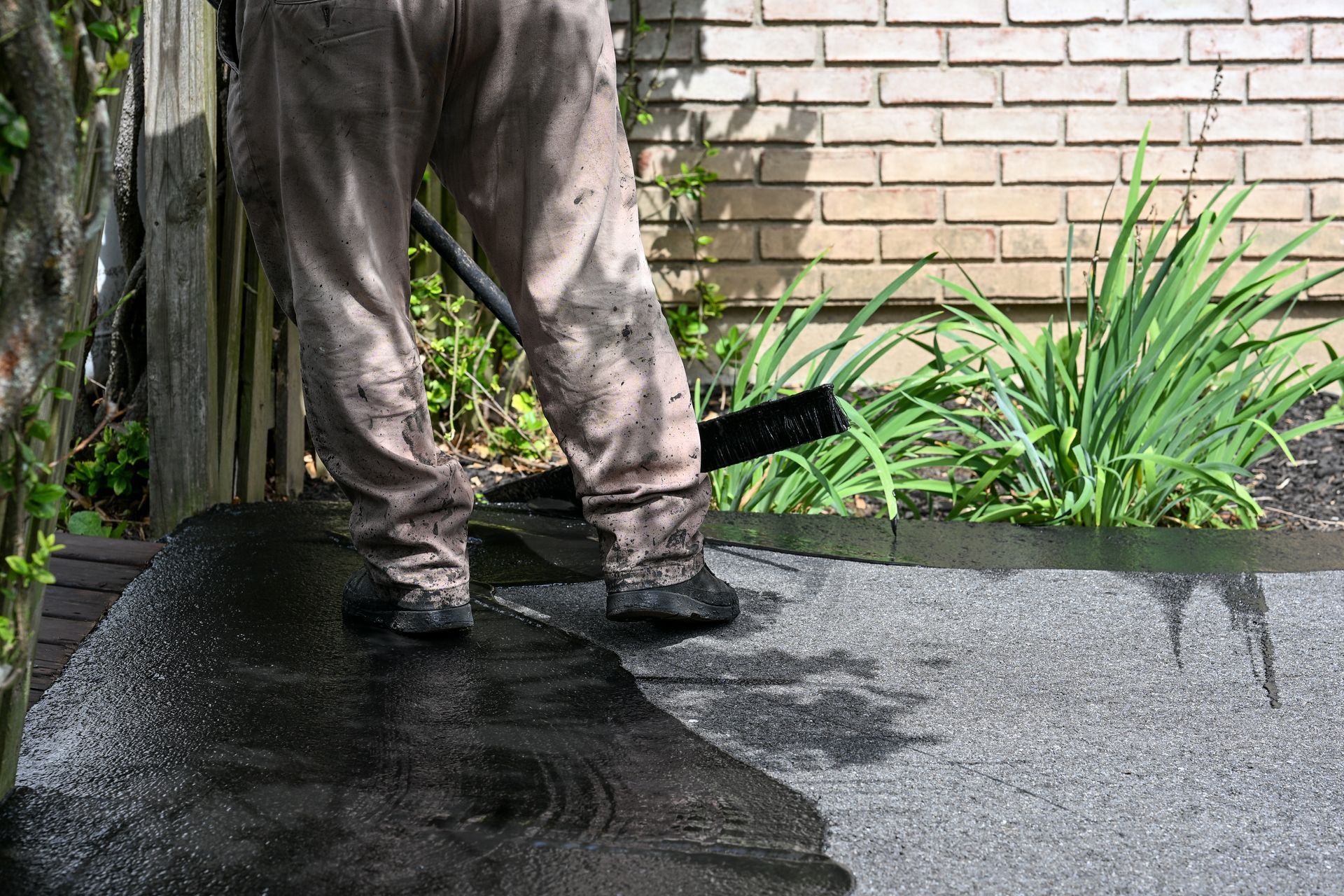 A man is cleaning a driveway with a broom.