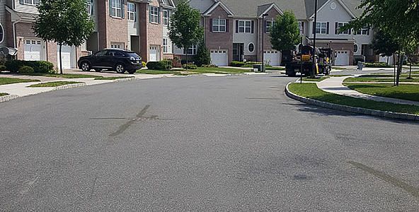 A black suv is parked on the side of the road in a residential neighborhood.