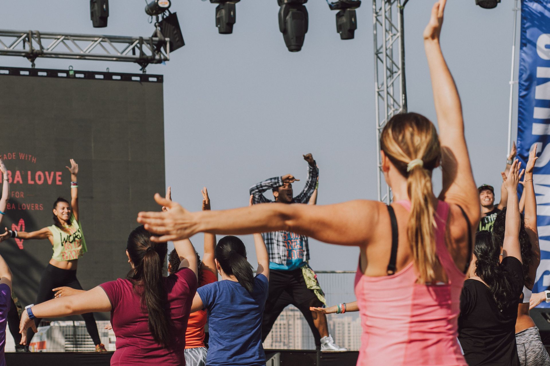 Group fitness class with arms raised outdoors at an event