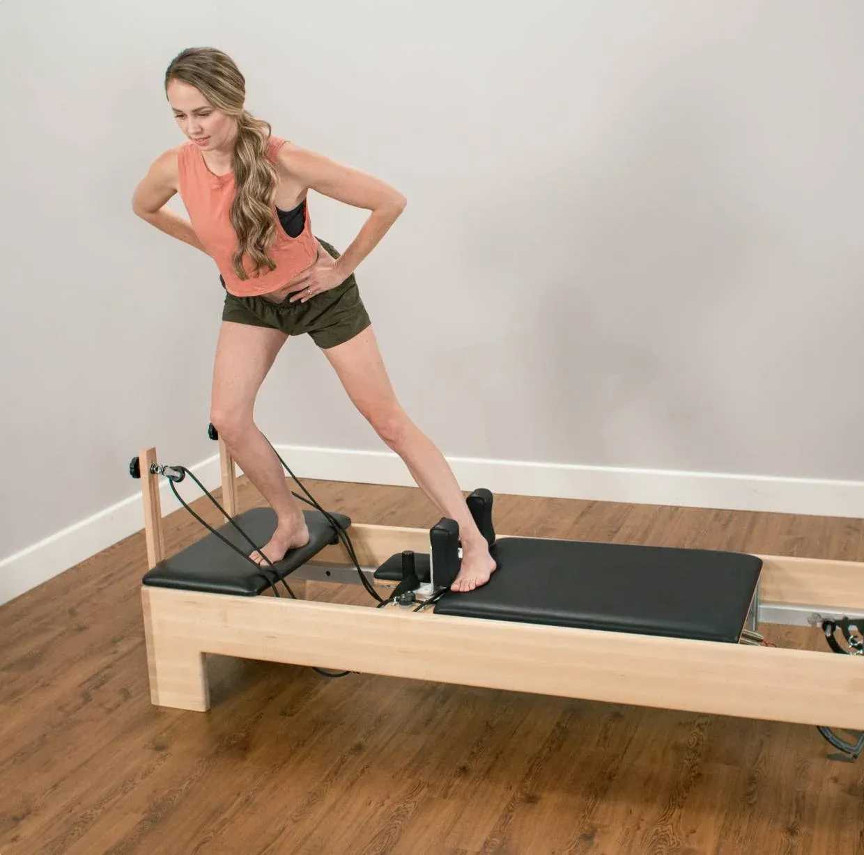 Woman in a lunge stretch using a Pilates reformer strap