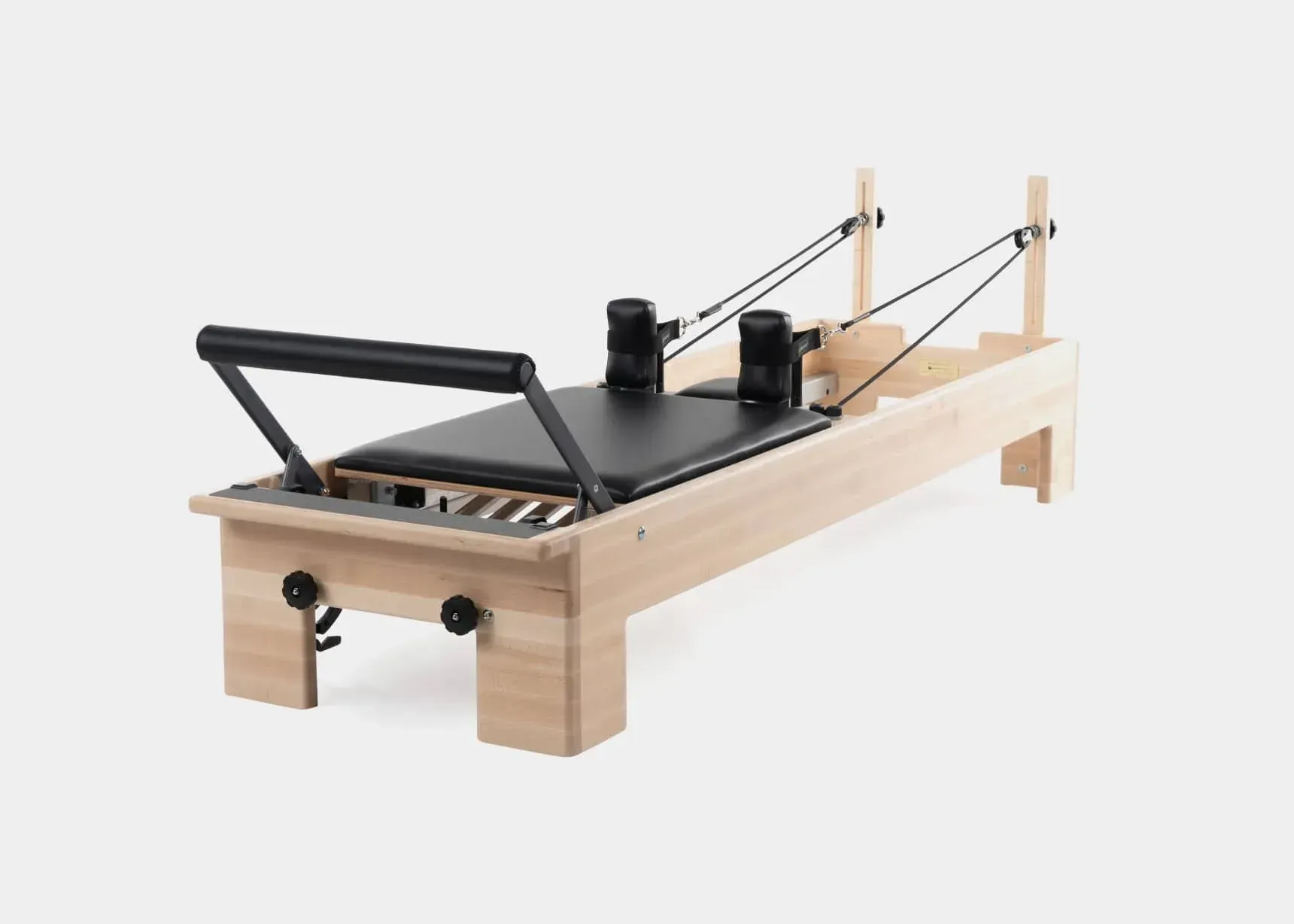 Wooden Pilates reformer machine with black upholstery in the studio