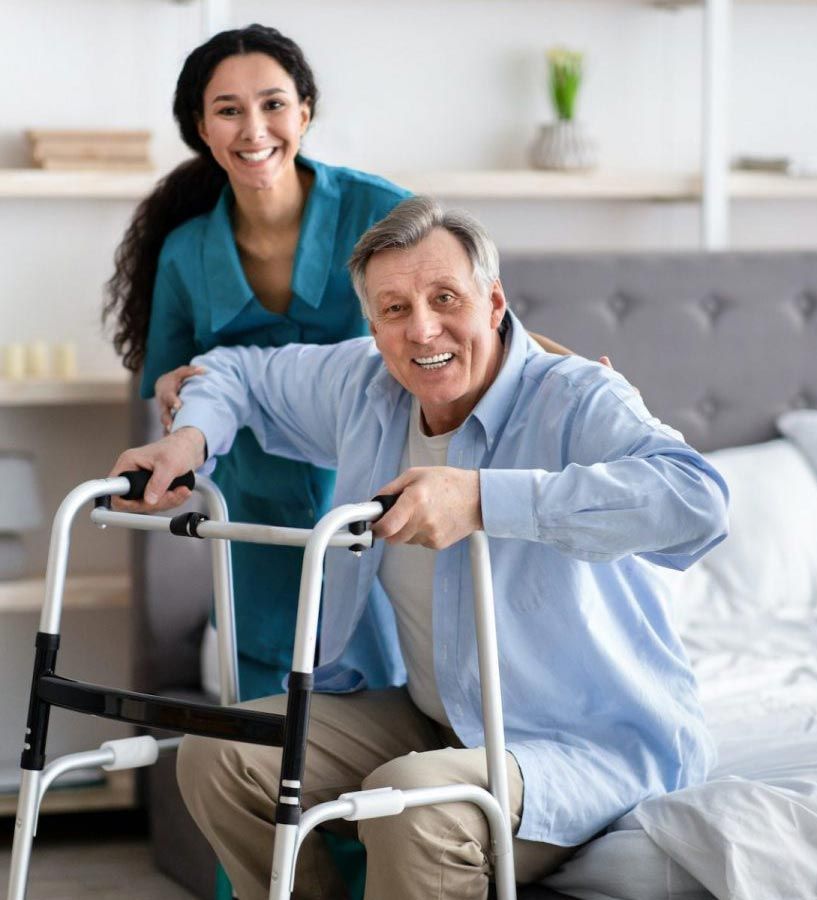 A woman is helping an elderly man use a walker.