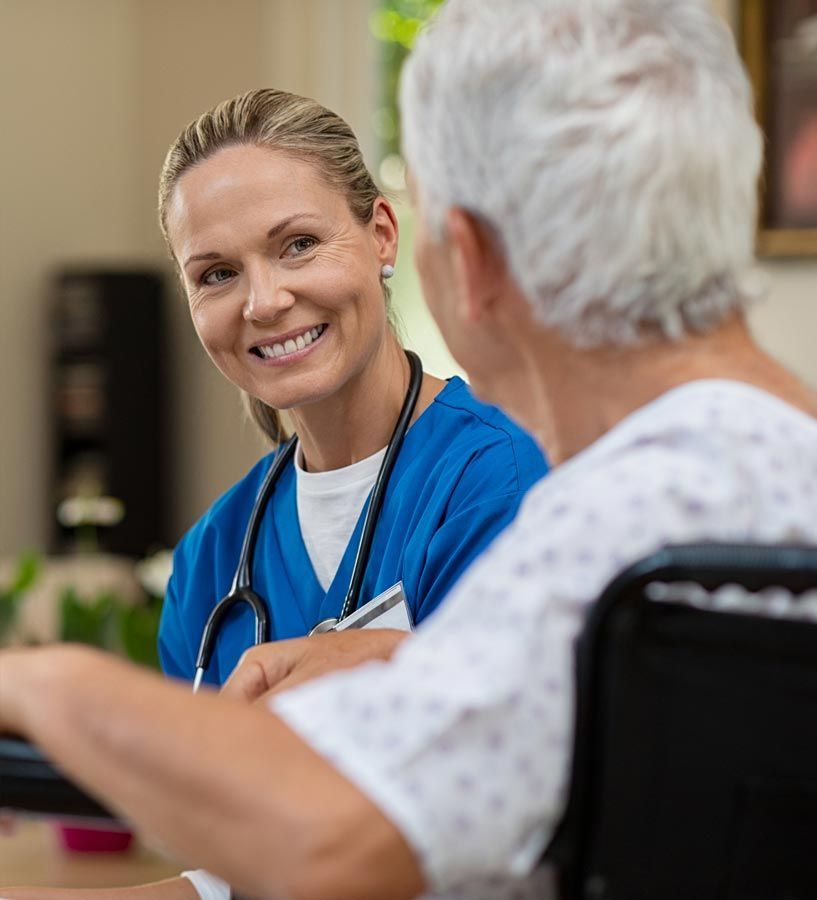 A nurse is talking to an elderly woman in a wheelchair.