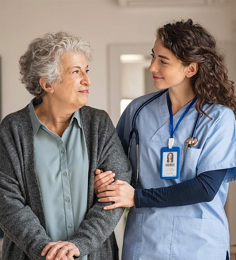 A nurse is hugging an older woman in a hospital room.
