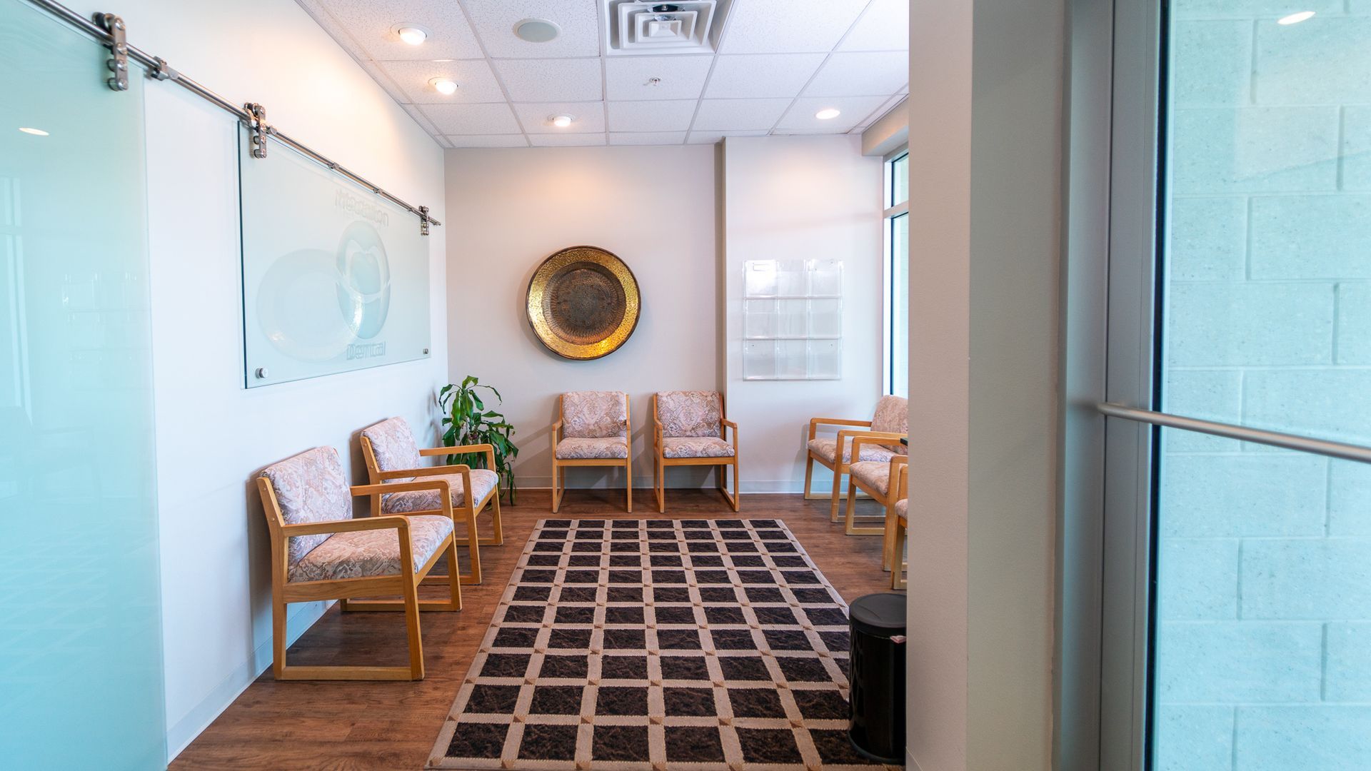 A waiting room with chairs , a rug and a picture on the wall.