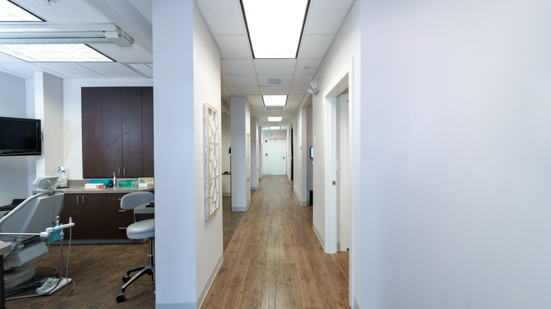 A long hallway in a dental office with a dental chair in the middle.