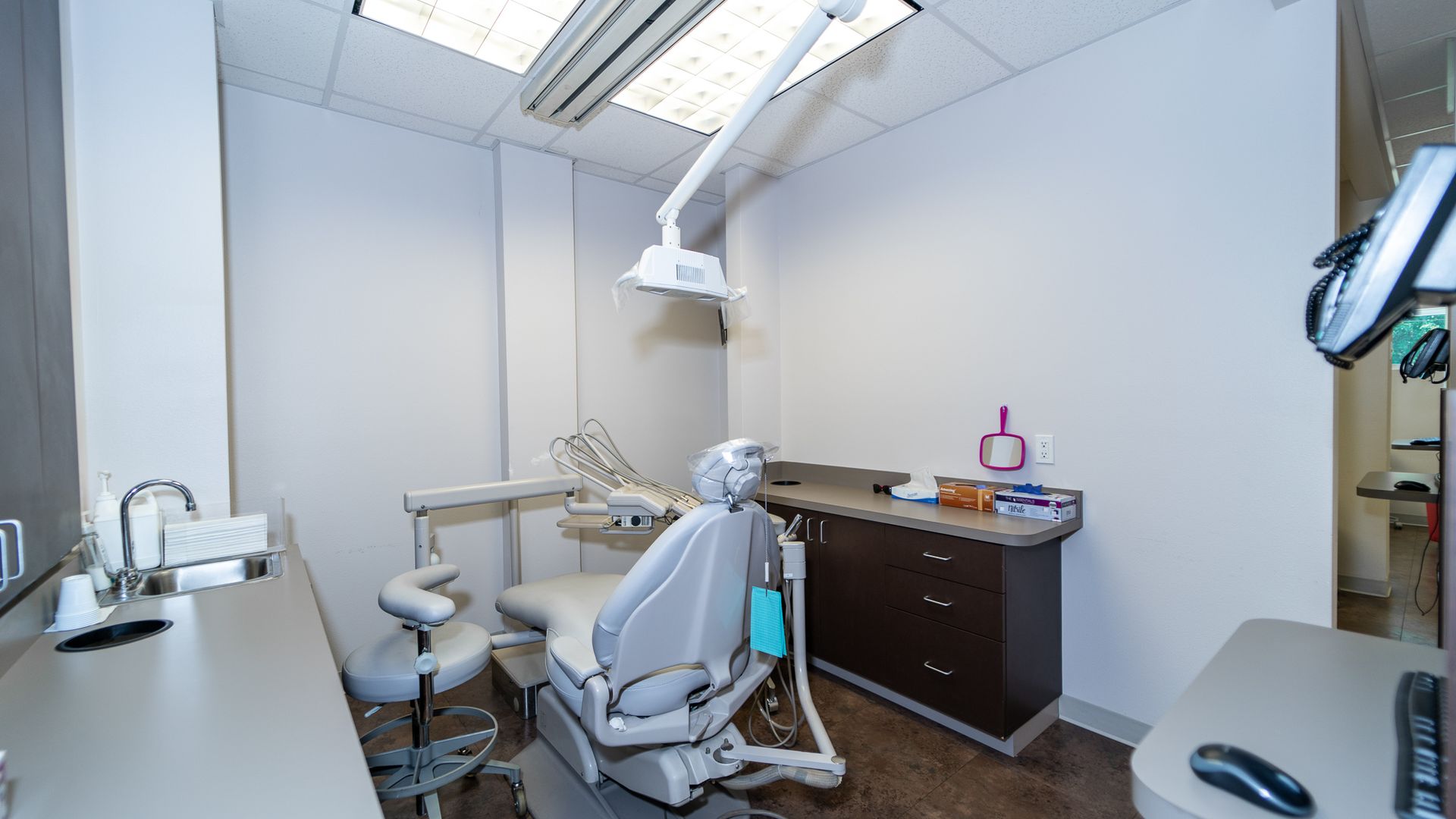 A dental office with a dental chair and a desk.