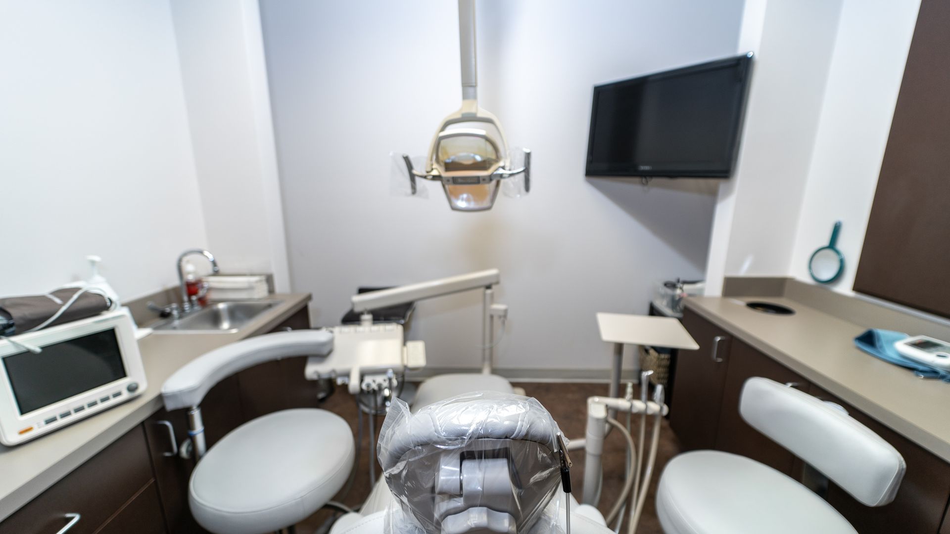 A dental office with a dental chair and a monitor.
