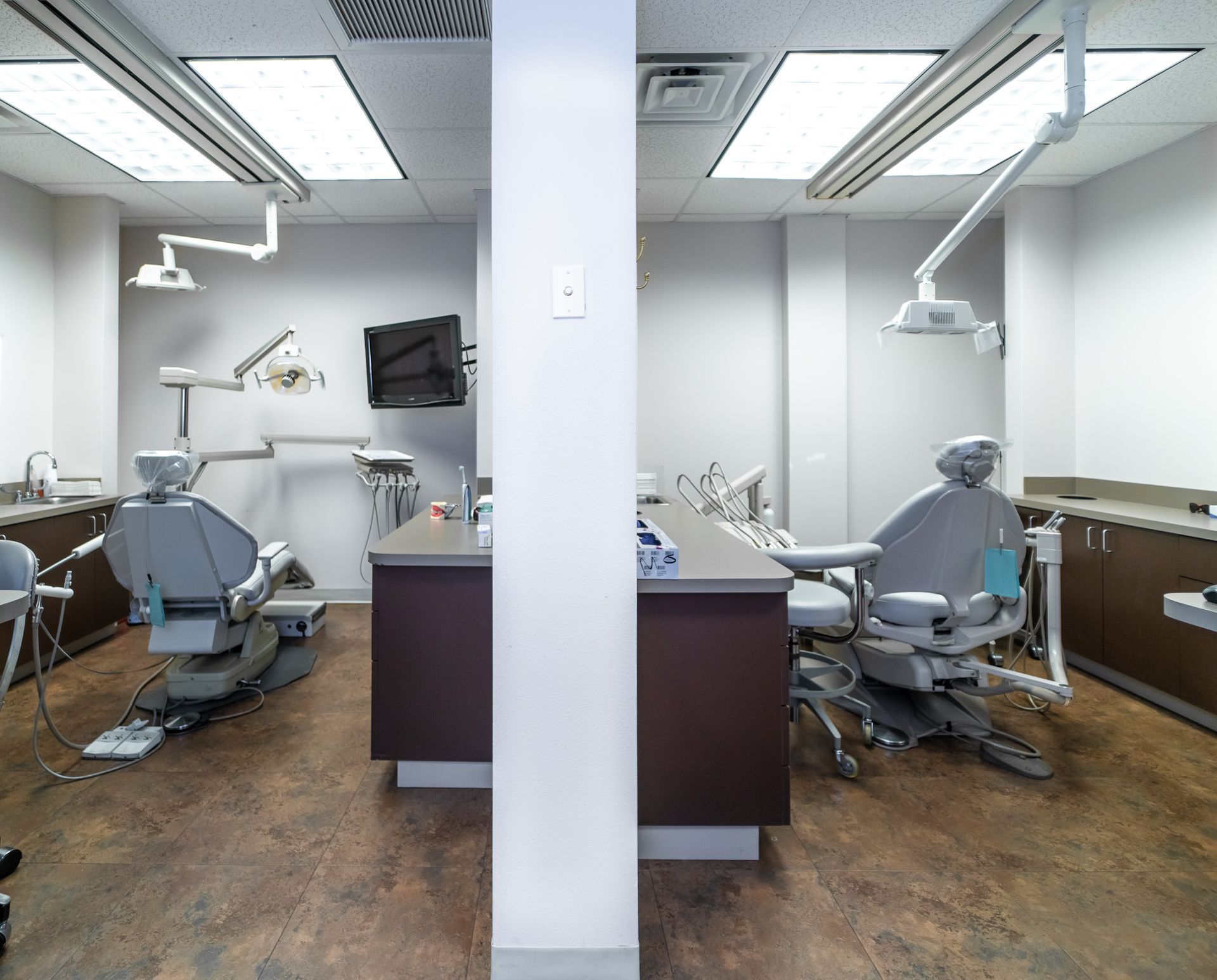 A dental office with two dental chairs and a tv on the wall