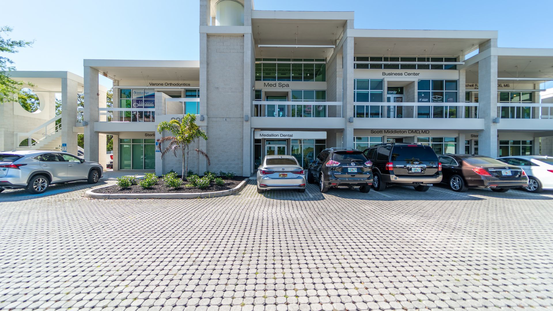 A row of cars are parked in front of a building.