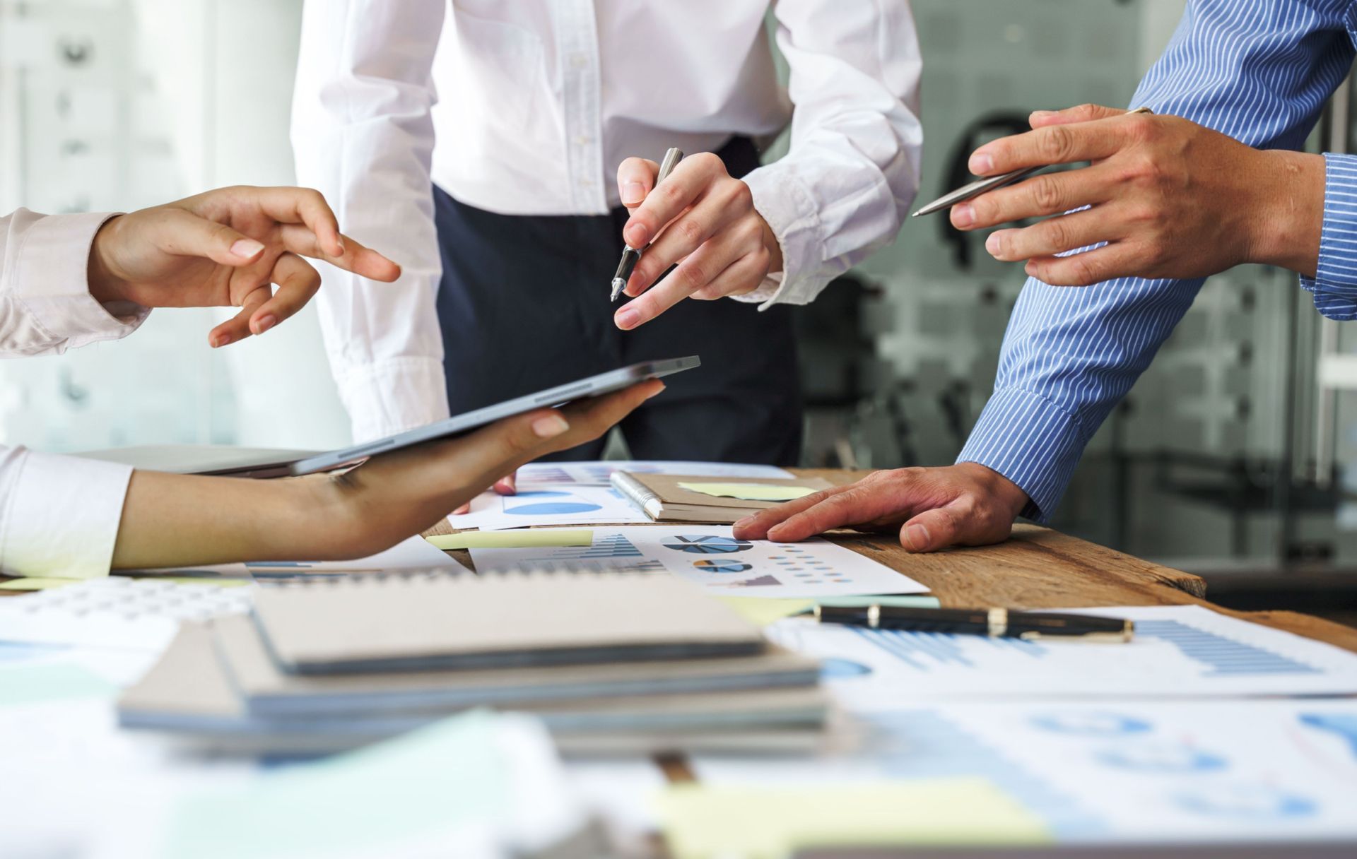 discussing+in+valuation+data+in+meeting+room-+three+business+people+with+accounting+paper+charts