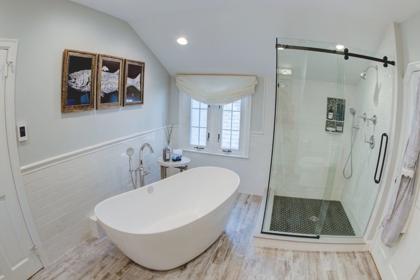 Elegant white bathroom with a freestanding tub, glass shower, and artwork on the wall.