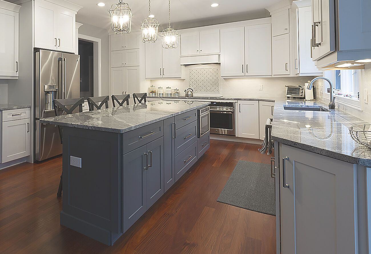 Modern kitchen with white cabinets, gray island, stainless steel appliances, hardwood floor.