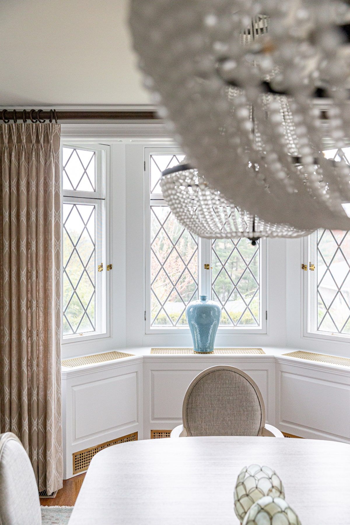 Elegant dining room with arched windows, a blue vase, and a crystal chandelier.