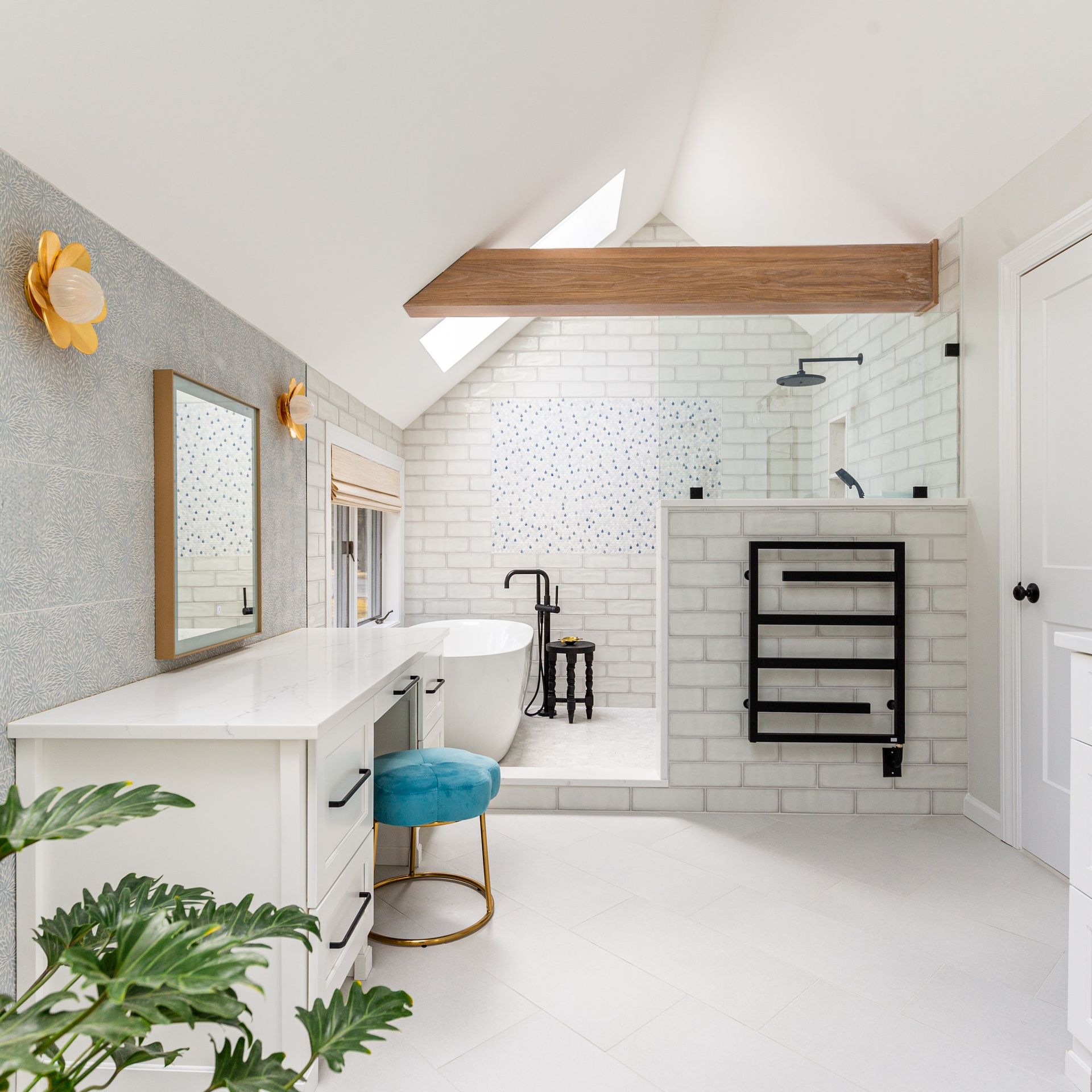 Bright white bathroom with a vanity, bathtub, and shower. Features skylight, exposed beam, and colorful accents.