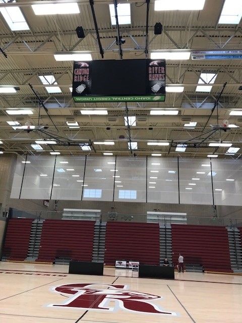 Basketball court with scoreboard and bleachers; SR logo on the floor.