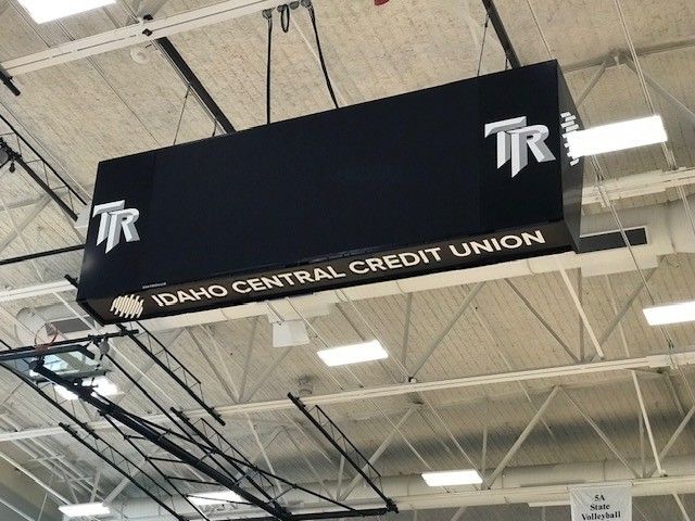 Black sign hanging from a ceiling with 
