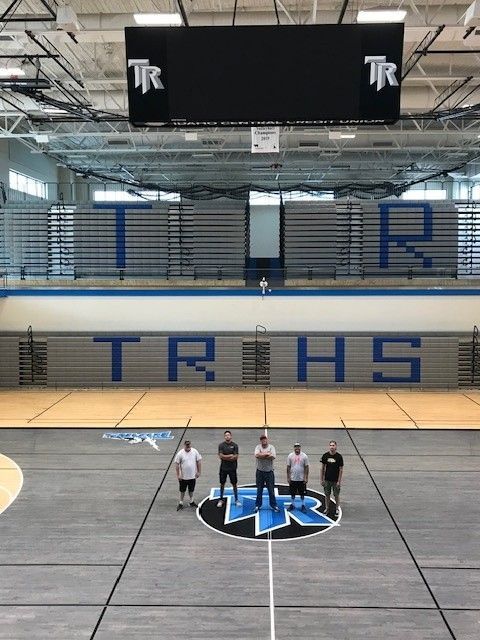 Five men standing on a basketball court under large
