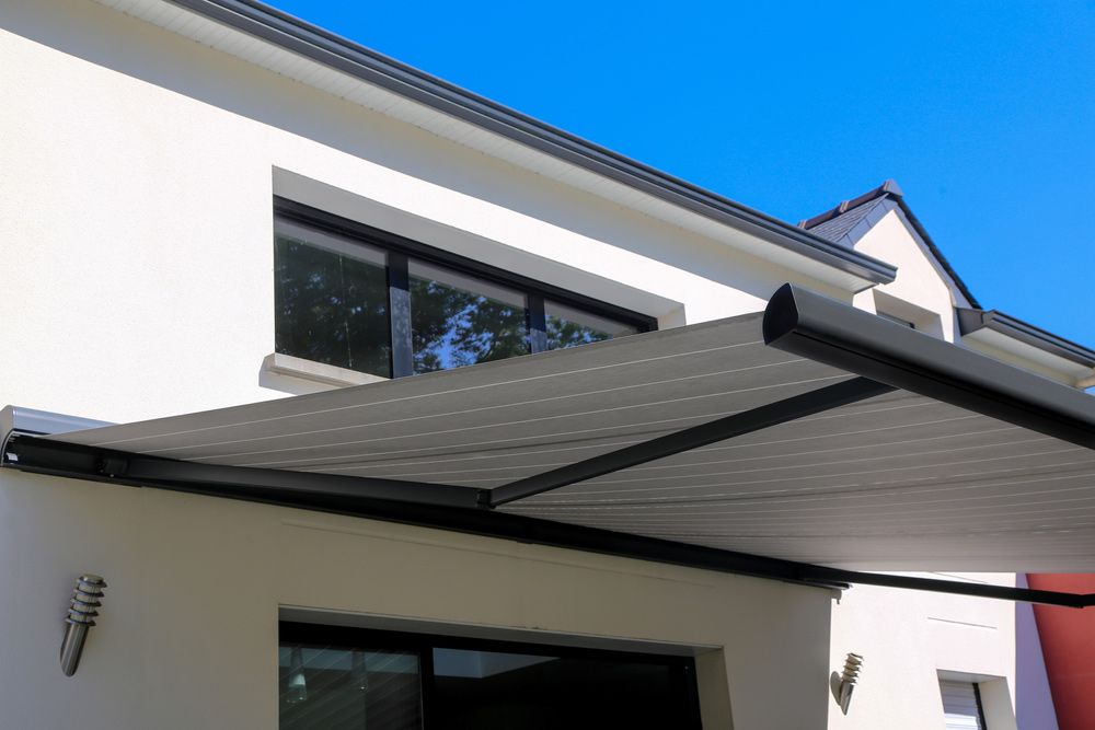 A White House With A Black Awning On The Side Of It — Gaeta's Upholstery Blinds & Awnings in Grafton, NSW