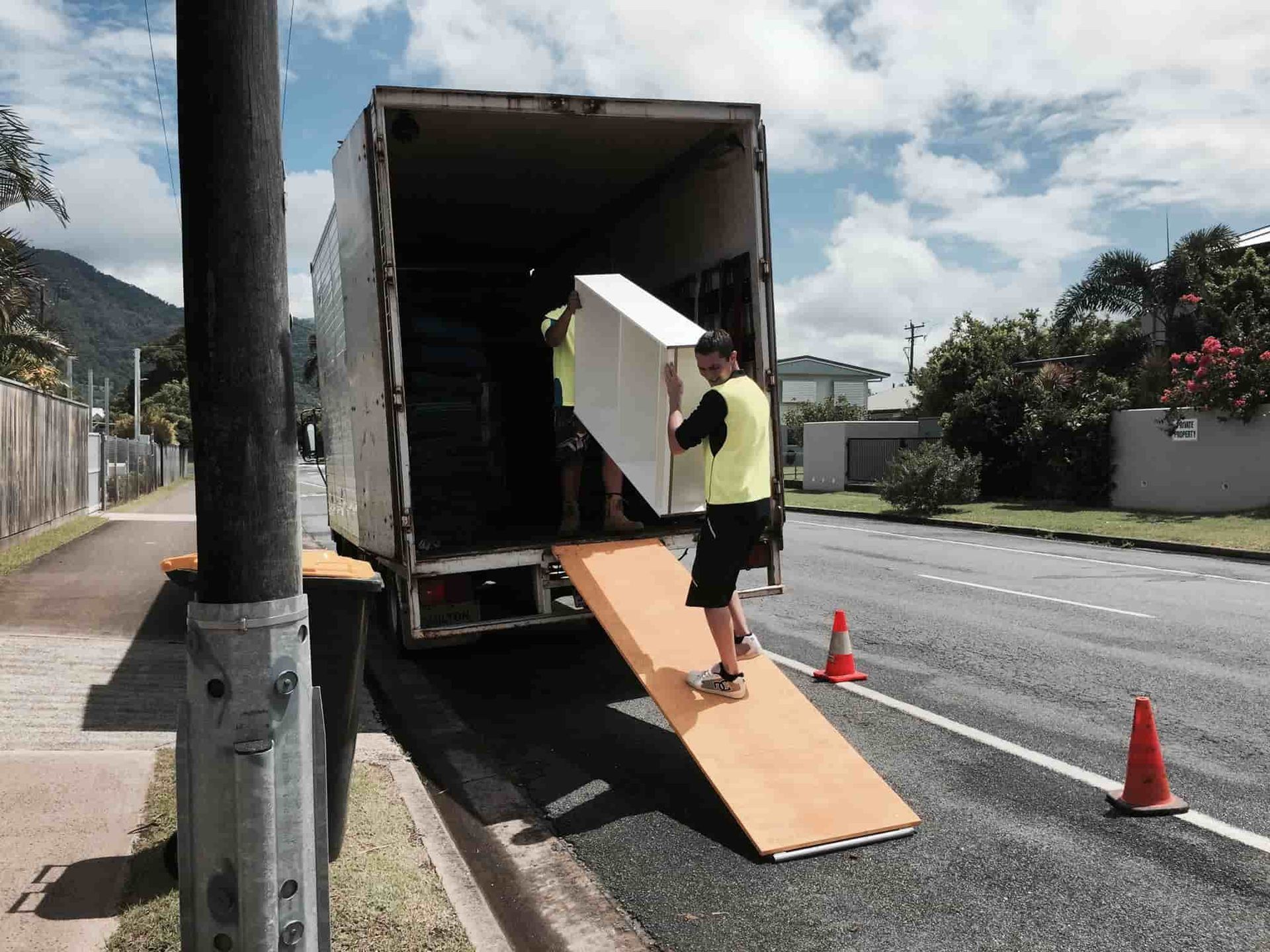 Workers Unload a Shelf From a Parked Moving Truck — Cairns Mini Movers In Mount Sheridan, QLD