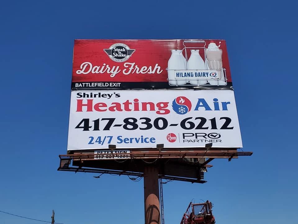 Billboard for Dairy Fresh and Shirley's Heating & Air against a blue sky.