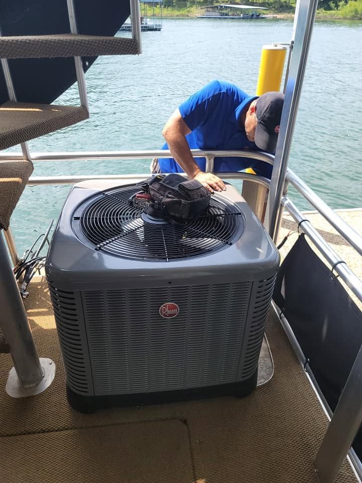 Mechanic inspecting an outdoor HVAC unit on a dock beside the water