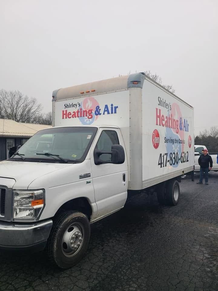White heating and air service truck parked on a wet street in front of a building