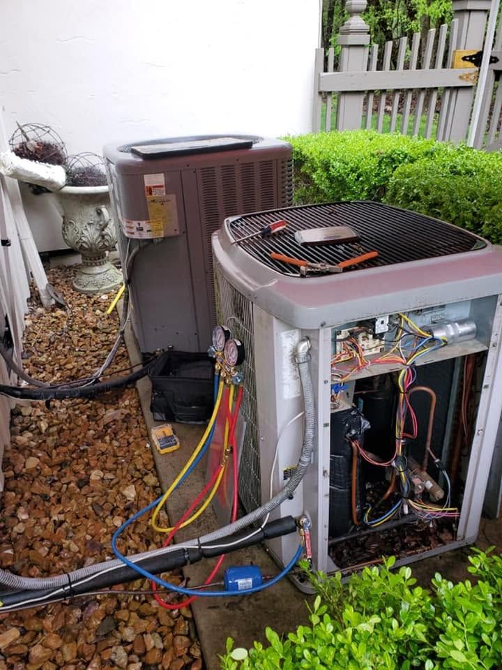 Two outdoor HVAC units beside a house, one open for repair with exposed wiring and tools.