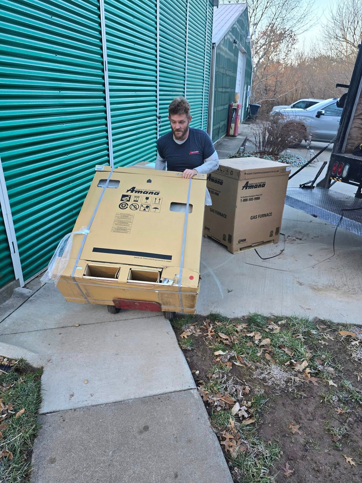 Person opening boxes on a sidewalk beside a green building and parked van