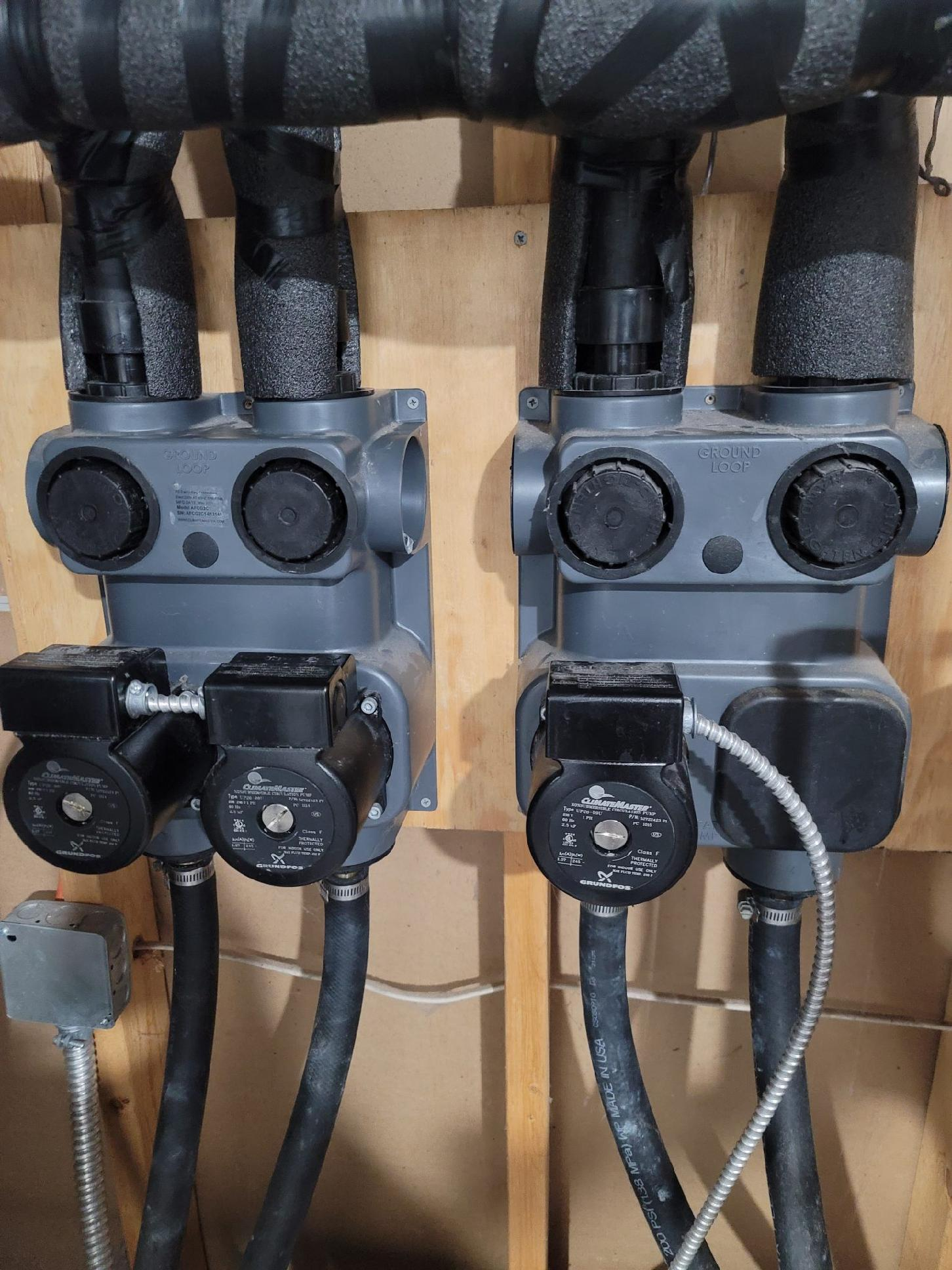 Two gray electrical junction boxes with black cables mounted on a wooden board.
